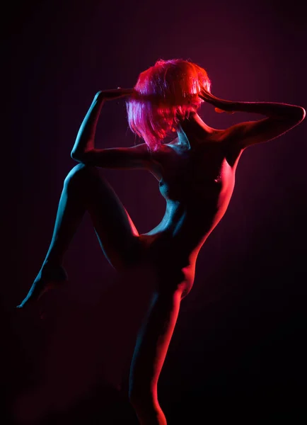 Naked dance girl, silhouette with beautiful body, nightclub or dance on stage, artfully motions. Seductive young woman in blonde wig. Passionate red color and ideal sexy body. Naked breast