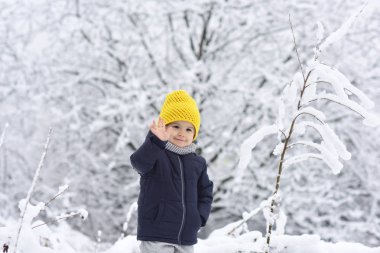 Neşeli çocuk elinde fotoğraf makinesi, Merhaba Merhaba kavramı sallayarak. Açık havada kar ile eğleniyor renkli kış giysileri sevimli küçük komik çocuk. Etkin açık havada eğlence kışın çocuklu