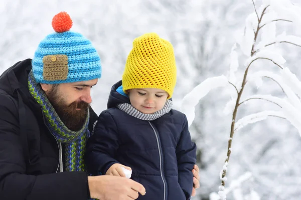 Χιονοστιβάδας παιχνίδι με τον πατέρα. Εξωτερική βολή του ευτυχής πατέρας και γιος χαμογελώντας. Νεαρός άνδρας και το μικρό αγόρι βλέποντας χιονοστιβάδας στο χέρι το παιδί και να απολαμβάνει τον χειμώνα με τα πόδια μαζί — Φωτογραφία Αρχείου