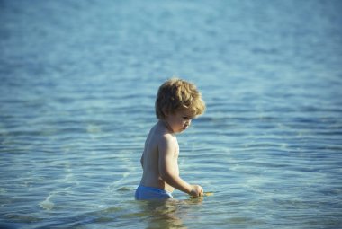 Küçük çocuk yüzmeyi suya gider. Açık mavi su, yaz günü. Yalnız çocuk çocuk yalnız denizde yüzüyor. Aile tatil deniz kenarında. Doğal arka plan. Çocuklar için eğlence tatil. Okyanusta şirin çocuk