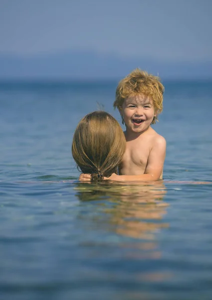 かわいい男の子は、海で笑います。彼女の子供を持つ母泳ぐ。海岸に家族の幸せな休暇。夏休みの間に家族の概念。家族でエコ観光。笑顔の子どもたちのレクリエーション休日 — ストック写真