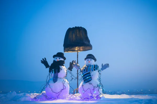 Modrá zimní obloha se sněhuláky vpředu. Slavnostní atmosféru osvětluje velká černá lampa. Slavnostní atmosféra venku. Veselé Vánoce. — Stock fotografie