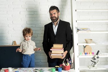 Çocuk eğitimi. Sınıfa, okula dönün. Okul kitapları kütüphanesi, profesör ve öğrenci birlikte edebiyat okuyorlar, sevimli bir çocuk kitap okuyor. Baba ödevlere yardım et. Kitapları olan okul çocuğu..