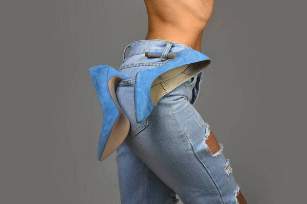 Тонкая девушка в джинсах. Женские джинсы на витрине. Джинсовые шорты для женщин на сером фоне. Модные туфли на каблуках. Девушка сняла туфли. Соблазнительная чувственная женщина
.