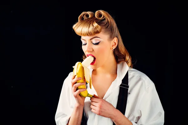 Banana nella bocca femminile. Bella giovane donna con uno spuntino. Gustosa banana e ragazza su uno sfondo nero . — Foto Stock