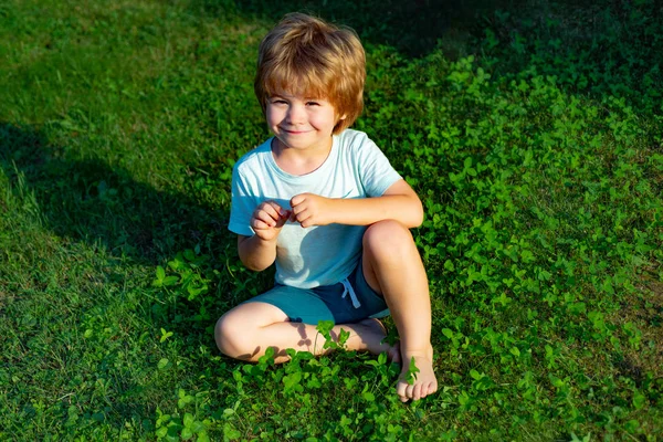 Un chico en la hierba. Chico feliz en el césped verde. Césped cerca de la casa familiar. Los niños sonríen en un día soleado . — Foto de Stock