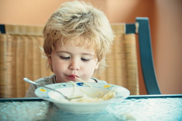 Милый ребенок со спагетти. Забавный мальчик ест макароны. Обед для дошкольников . — стоковое фото