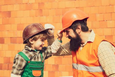 Koruyucu miğferler. İnşaat konsepti. - Brick. Takım çalışması. İki inşaatçı. Çocuk ve yetişkin. Profesyonel büyüme. Kariyer. Karnaval meslekleri. Bir çocuk ve bir adam şantiyede..