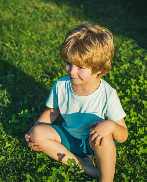 Niño en la hierba. Humor de primavera o verano. Niño y la naturaleza a pie . — Foto de Stock