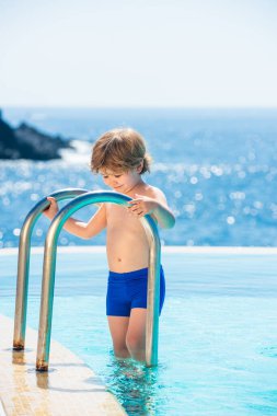 Havuz zamanı. Sudaki mutlu çocuk. Havuzlu deniz manzarası. Lüks yaz kaplıca tatilleri.