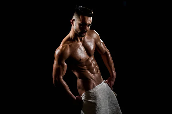 Homem sexy com toalha. Chuveiro após o treino. Homem em um fundo preto com músculos e uma toalha branca . — Fotografia de Stock