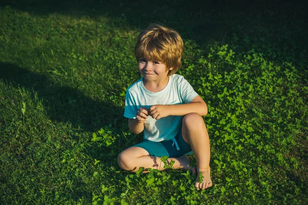 Caza de huevos. Children and Egg Hunt. Lindo niño hermoso está sentado en la hierba. Chico primavera. Tiempo de Pascua . —  Fotos de Stock