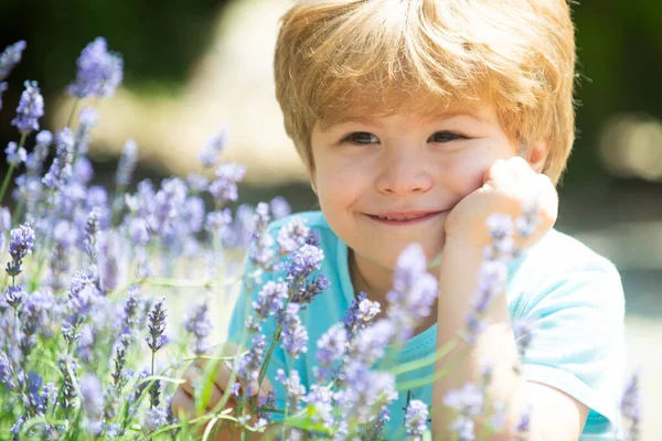 Retrato de primavera. Relájese en el jardín del hogar. Niño cerca del arbusto de lavanda . — Foto de Stock