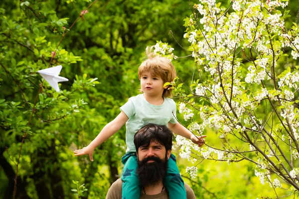 Ονειρική πτήση. Πατέρας και γιος ονειρεύονται ένα αεροπλάνο. Περπατήστε στον κήπο άνοιξη με ένα αεροπλάνο παιχνίδι. — Φωτογραφία Αρχείου