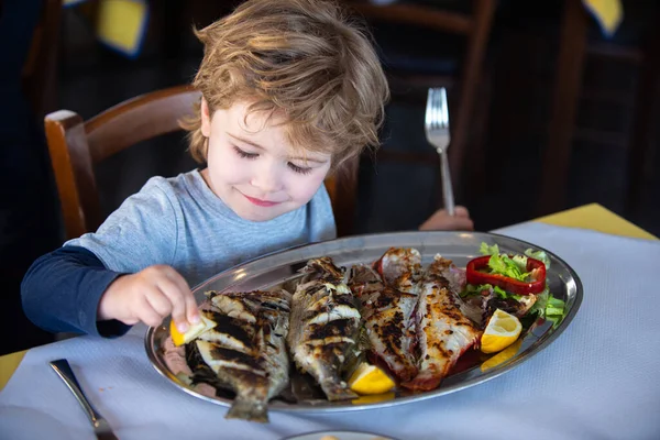 Pesce per il cibo. Bambino wuth limone e piatto di pesce farina. Cena in ristorante di mare. Frutti di mare con iodio per una dieta sana . — Foto Stock