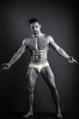 Karantina sırasında evde spor. Erkek, evde Coronavirus 'a karşı egzersiz yapıyor. Siyah arka planda poz veren adam kaslarını gösteriyor. Bronzlaşmış derisi olan genç vücutçunun mükemmel, bitkin vücudu..