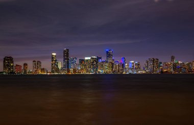 Miami, Florida, ABD silueti. Biscayne Körfezi 'nden görüntü. Miami 'nin güzel şehrinde bir gece. Miami 'deki gökdelenler. Florida 'da okyanus kenarında tropik bir gece. Şehir Işıkları.