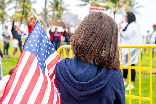 Amerikai zászló és gyerek a bemutatón. Kis hazafi. Az amerikai zászlós lány. Amerikai gyerekek. Egy gyermek tiltakozik a koronavírus-korlátozások ellen. Miami tüntetők. Polgári jogok. A demokrácia. — Stock Fotó