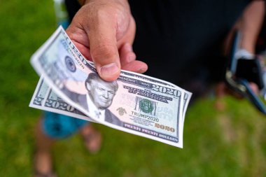 Miami Beach, Florida, ABD - 10 Mayıs 2020 Donald Trump 2020. Trump 'ın portresi olan sahte bir dolar. Para için. Miami 'deki banknot. Elinde sahte para var. Trump Seçmenleri. Seçim Kampanyası Finansmanı.
