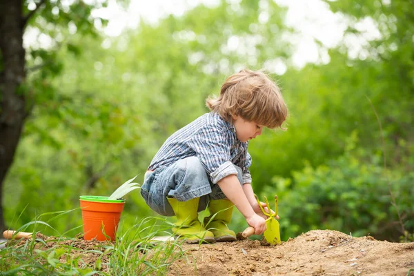 Junge auf einem Bauernhof gräbt mit Gartenwerkzeug den Boden um. Arbeit — Stockfoto