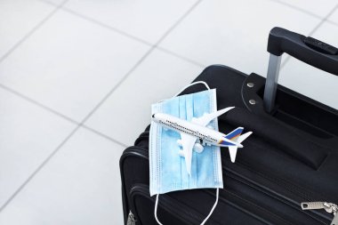 Tıbbi maske ve oyuncak bir uçakla seyahat çantası. Coronavirüs salgını sırasında seyahat yasağı.