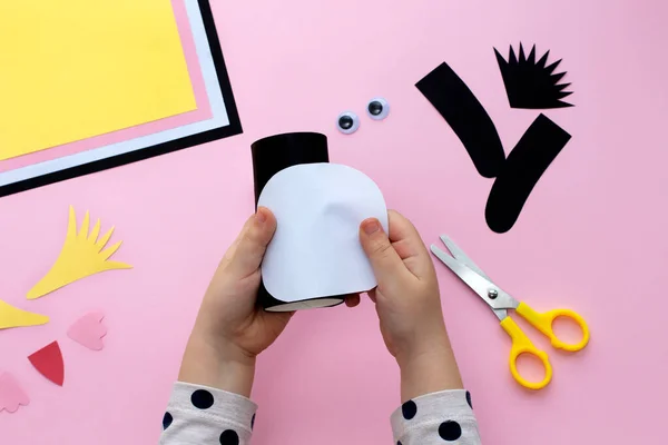 Making a penguin from colored paper and a roll of toilet paper. Children\'s art project. Step by step photo instruction. Step 3. Glue the roll with black paper and glue the white part.