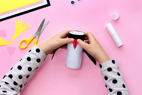 Making a penguin from colored paper and a roll of toilet paper. Children\'s art project. Step by step photo instruction. Step 5. Bend the beak piece in half and glue it.