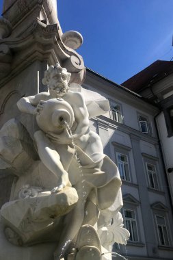 Su dolu bir kavanozu tutan antik bir mermer heykel.