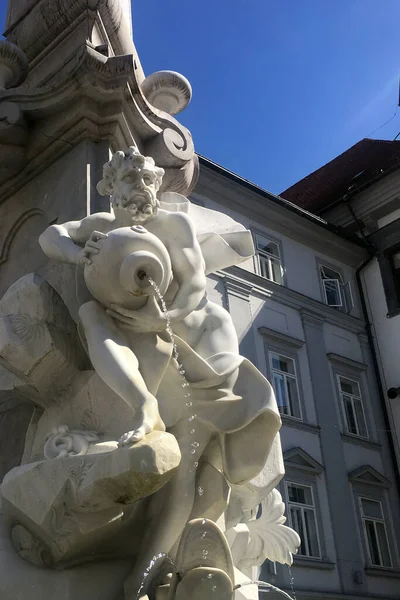 Su dolu bir kavanozu tutan antik bir mermer heykel.