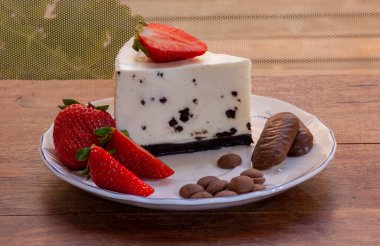Çikolatalı, çilekli ve ahşap arka planda çikolatalı orijinal cheesecake tarifi..