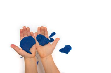 Çocuk ellerinde plasticine tutuyor ve beyaz bir arka plan üzerinde renkli hamurlar geveliyor..