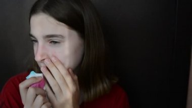 Alerjisi olan hasta bir kız burnunu peçeteye siliyor, gözlerini ovuyor, burnunu siliyor..