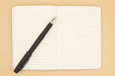 Turuncu arka planda açık siyah kalemli bir defter, iş planlama konsepti. Mesaj için yer var. Kapatın. Model