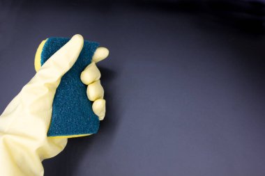 Siyah arka planda sarı eldivenli sünger tutan bir kadın. Üst Manzara, kapat. Temiz ev kavramı, metin için boşluk