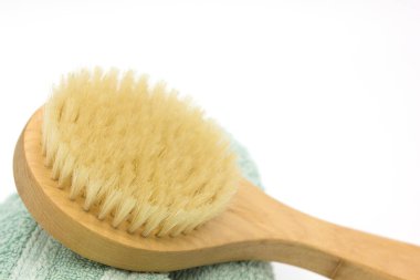 Beyaz arka planda havlunun üzerinde kuru vücut masajı ahşap eko fırçası. Pürüzsüz ve yumuşak cilt spa 'sı için bir araç. Kapatın. Metin için boşluk
