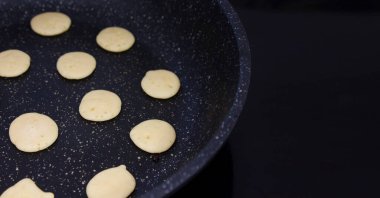 Küçük krep gevrekleri karantinaya alındı. Mini krepler mutfakta tavada kızartılır. Yemek pişirme süreci. Canlı fotoğraf kızartması