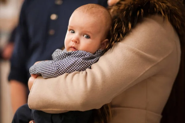 Baby op moeders handen in kerk doopsel ceremonie Stockfoto