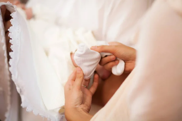 Mãe vestir pequeno menino pé com meia branca na igreja — Fotografia de Stock