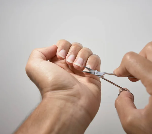 Eller beyaz arkaplanda tırnak kesiyor