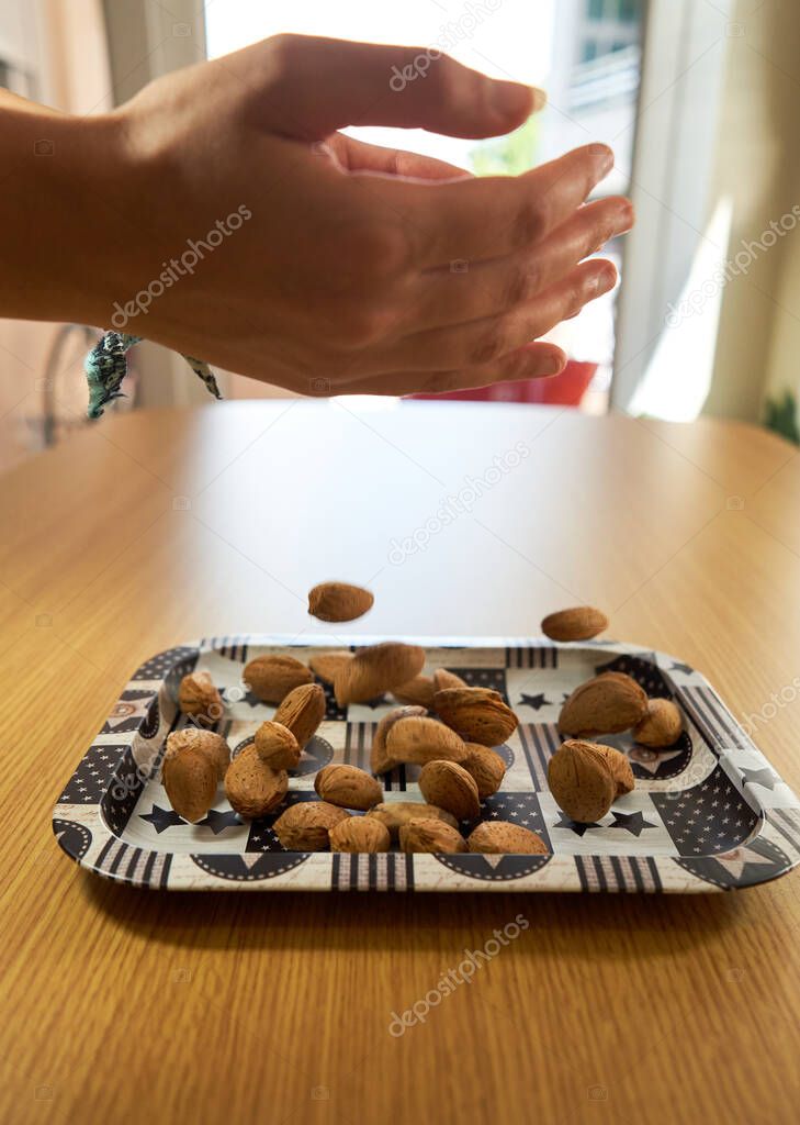 hands dropping almonds on table