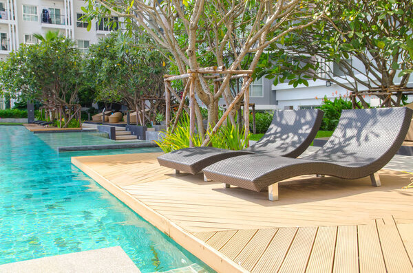 Открытый бассейн с голубой водой рядом с садом
.