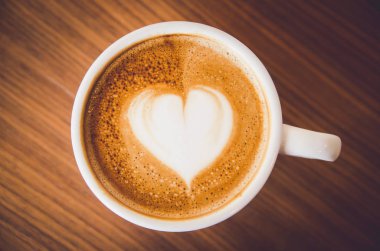 Kahve latte sanat ahşap arka plan üzerinde kapatın