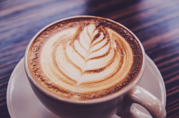 Taza de café arte latte en café de mesa de madera —  Fotos de Stock