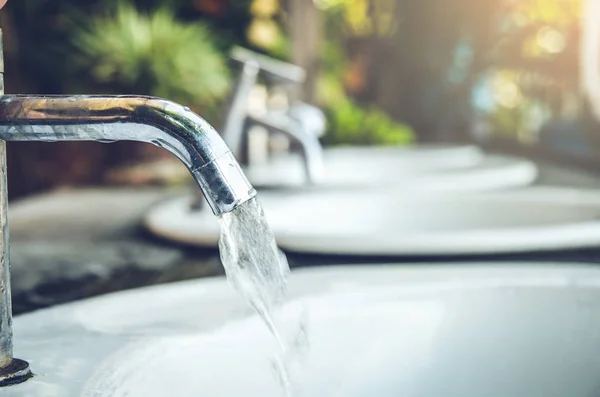 Waterkraan met waterdruppel buiten groen park achtergrond — Stockfoto