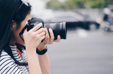 Bazı kadınlar DSR kameralarını ellerinde tutuyor ve şehirde fotoğraf çekiyorlar. 