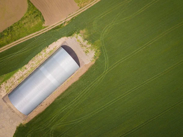 Aerial top down drone photo. Farm warehouse among green fields.