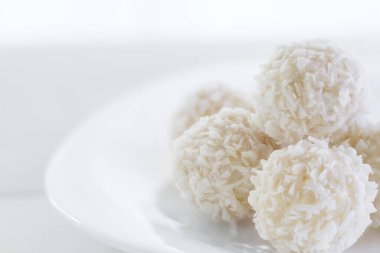 Çikolata kaplı tabakta şekerler ve kırsal ahşap arka planda parçalanmış hindistan cevizi. Hindistan cevizli mantar topları. Kıza romantik tatil hediyesi, kadın. Makro, kopyalama alanı, yüksek tuş atışı