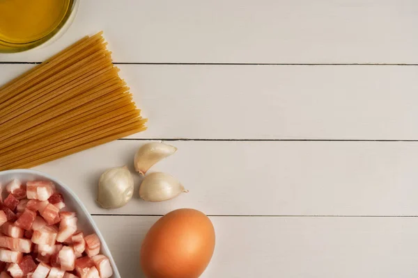 素朴な表面にイタリアのカルボナーラのための調理成分 パスタ パンチェッタとスパゲティ パルメザンチーズ ベーコン クリーム ニンニク オリーブオイル トップビュー コピースペース — ストック写真