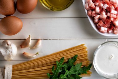 İtalyan carbonara 'sı için kırsal yüzeyde yemek malzemeleri. Makarna, pancetta, yumurta, pastırma, krema, roka, sarımsak, zeytinyağı. Geleneksel İtalyan mutfağı. Üst görünüm, kopyalama alanı, düz uzanma.