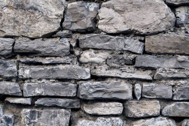 Gri duvarcılık, taş işçiliği, tuğla işçiliği. Beton, çimentoyla farklı gri taş yüzey. Kaya gibi kasvetli bir arka plan. Soyut hasarlı kentsel kirli kum taneli taş duvar